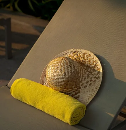 Handmade hat and yellow towel on a rooftop-pool sunbed